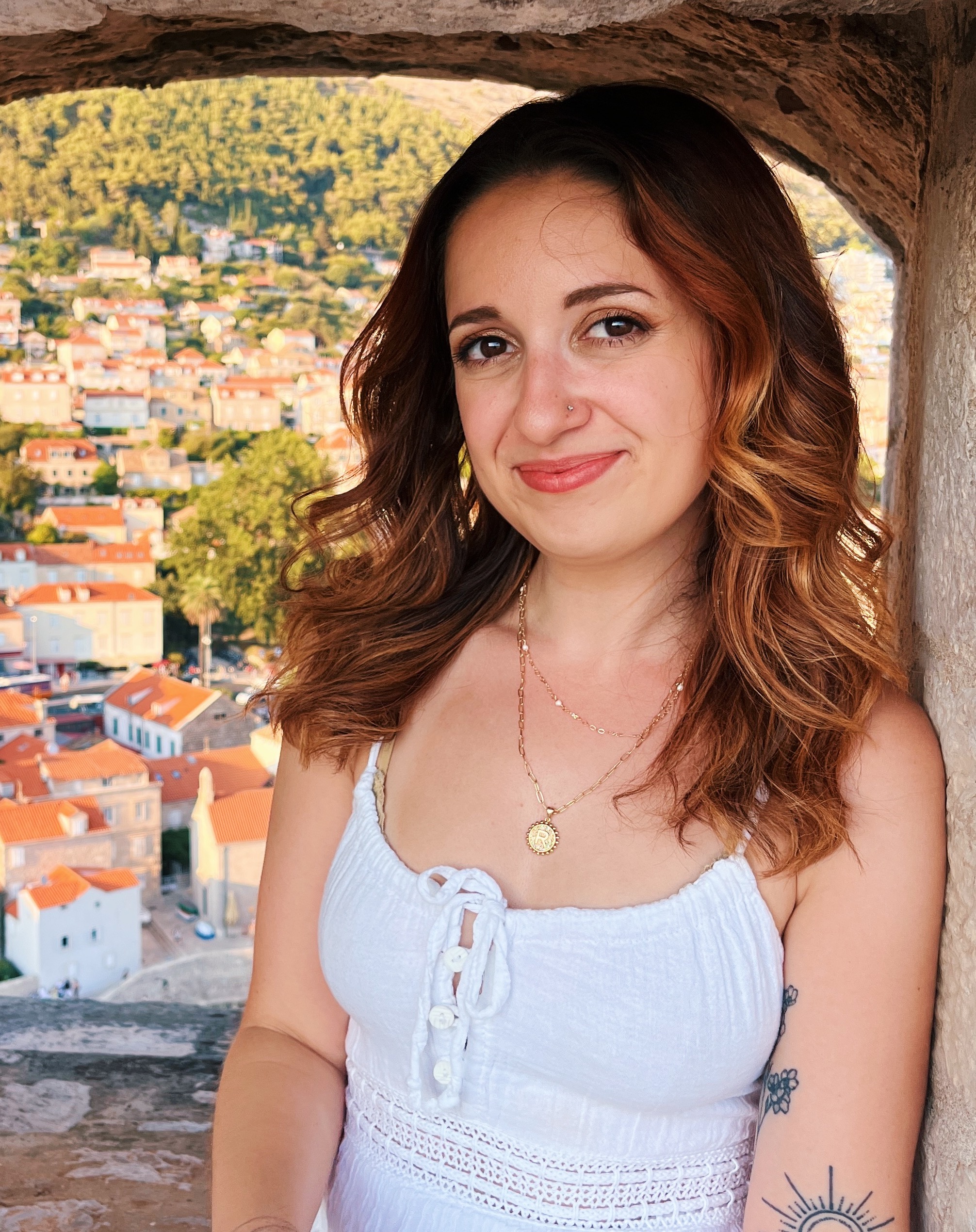 Rebecca Drew smiling, overlooking a coastal hillside town