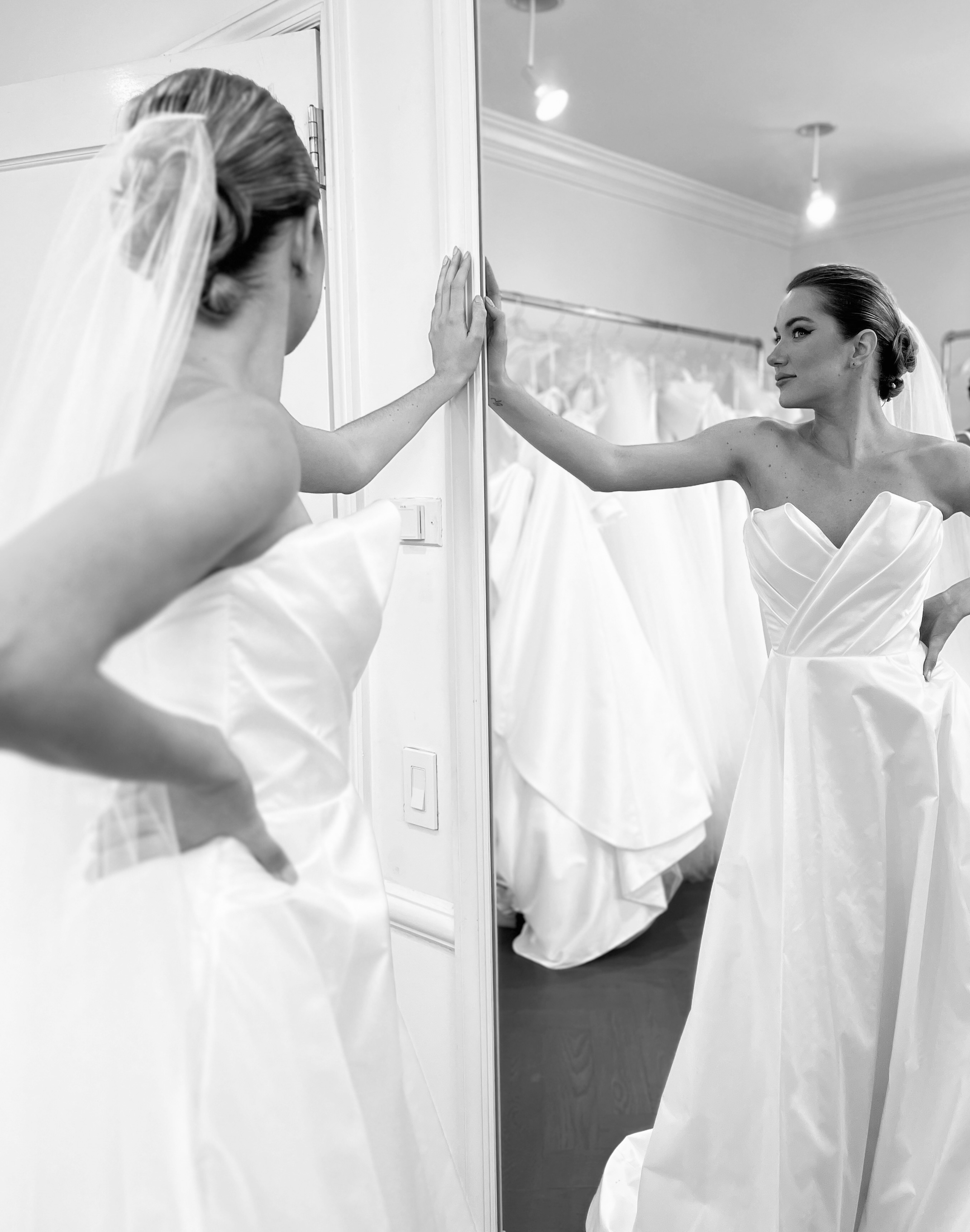Bride admiring her reflection in a bridal salon mirror while trying on her gown